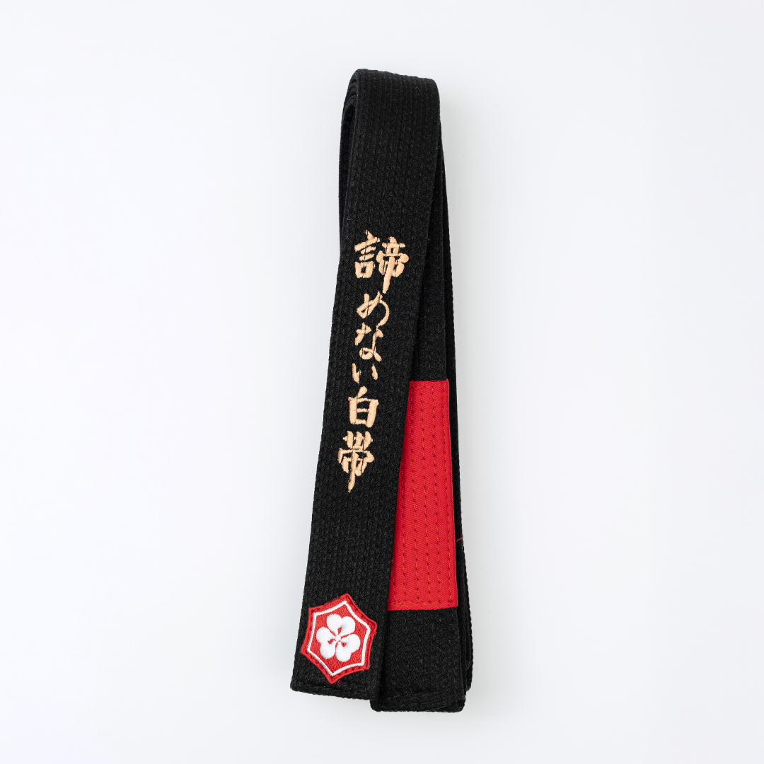 A WHITE BELT WHO NEVER QUIT EDITION — KAZE black belt with red bar and gold embroidery