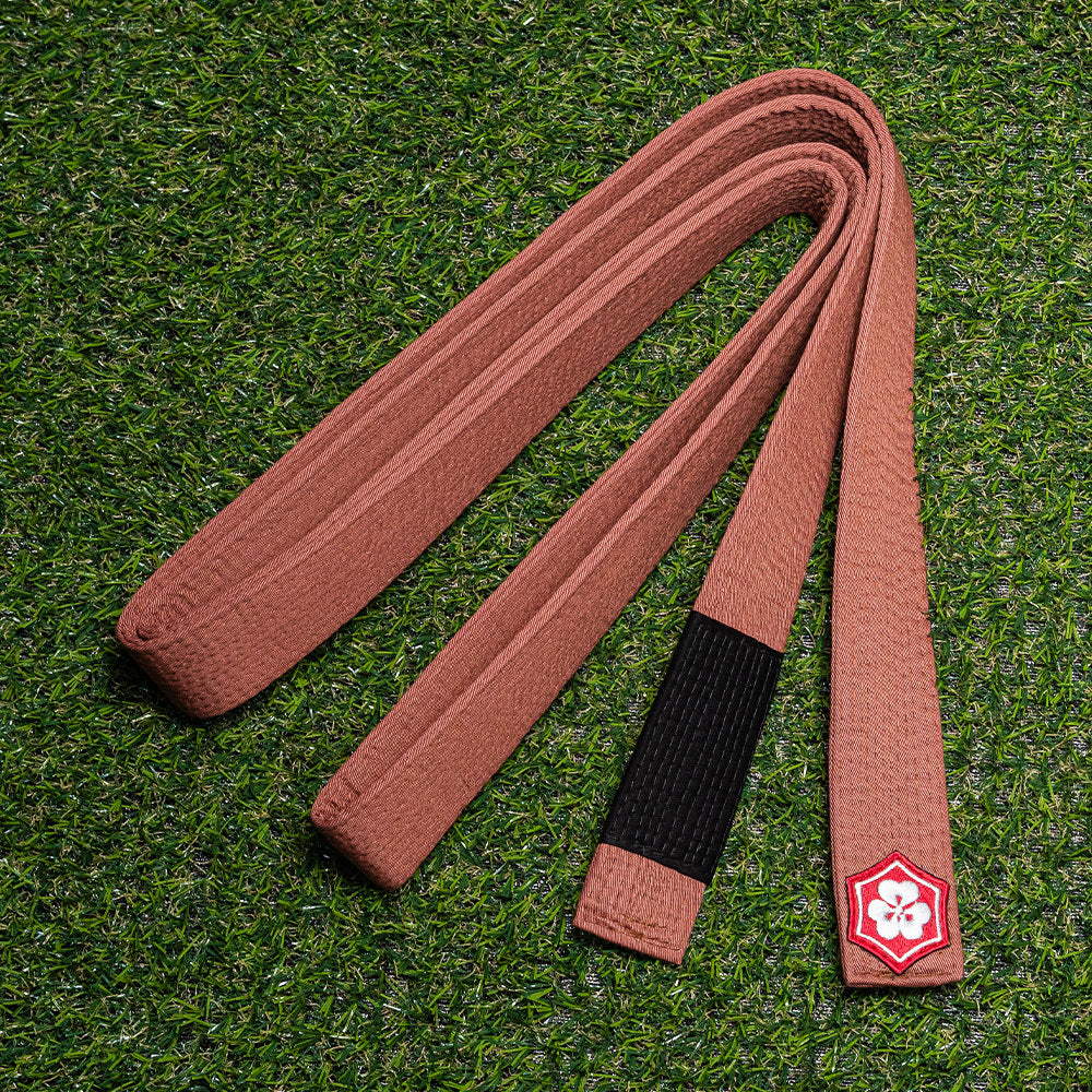 Brown KANJI Classic BJJ belt with a black rank bar on training turf