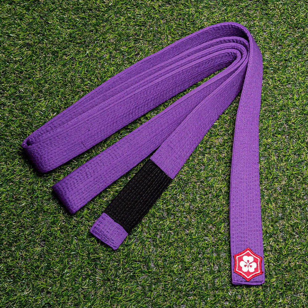 Purple KANJI Classic BJJ belt with a black rank bar on training turf