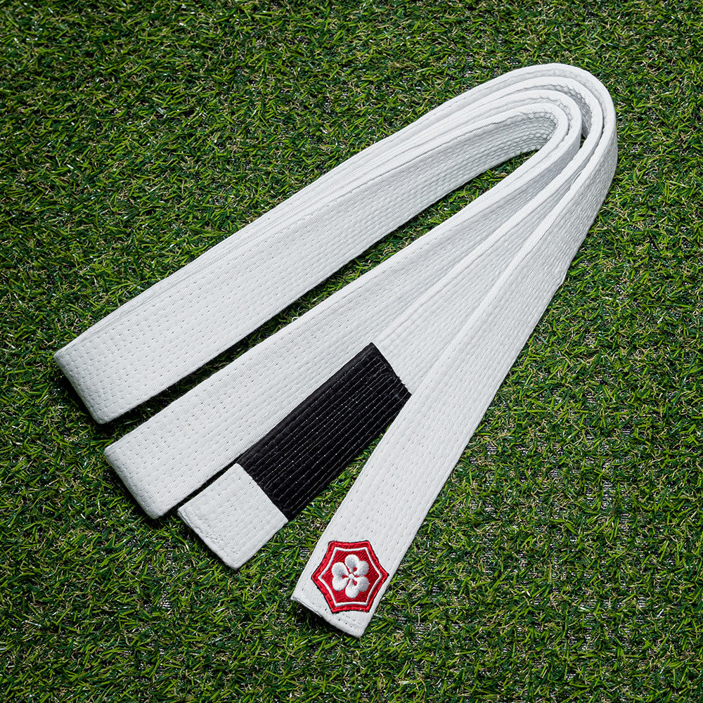 White KANJI Classic BJJ belt with a black rank bar on training turf