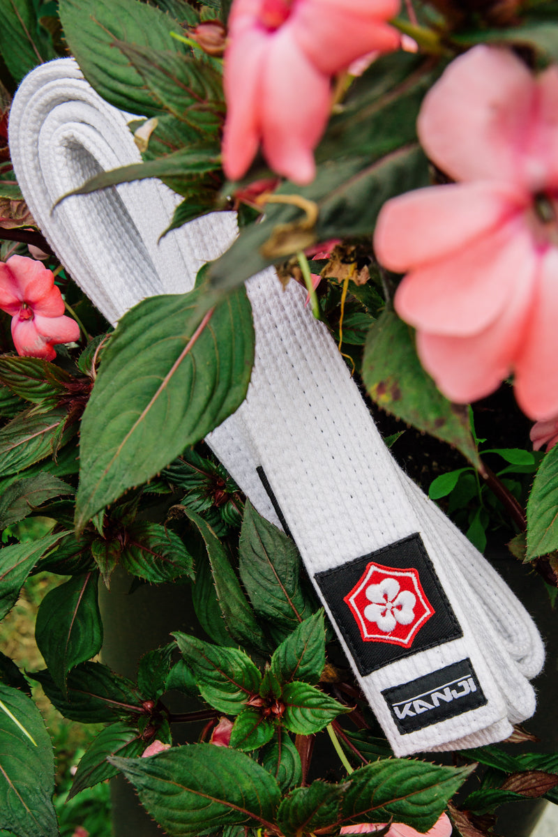 White KANJI KATANA BJJ belt among pink flowers