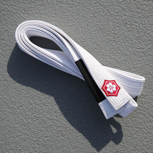 White KANJI KAZE BJJ belt with a black rank bar folded on concrete