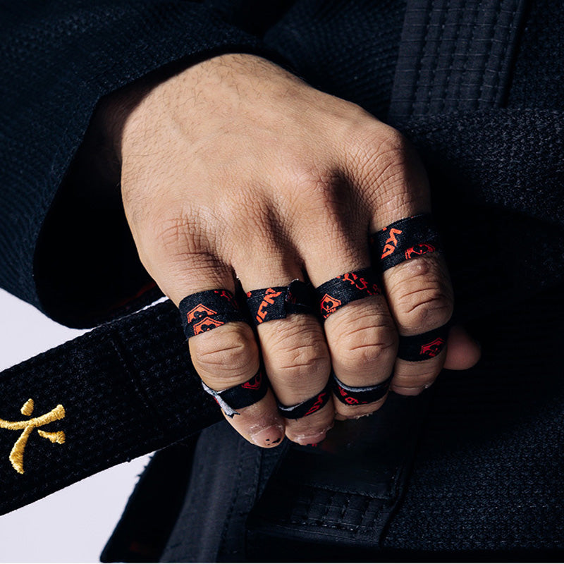 Jiu-jitsu athlete gripping a belt with fingers wrapped in black KANJI finger tape